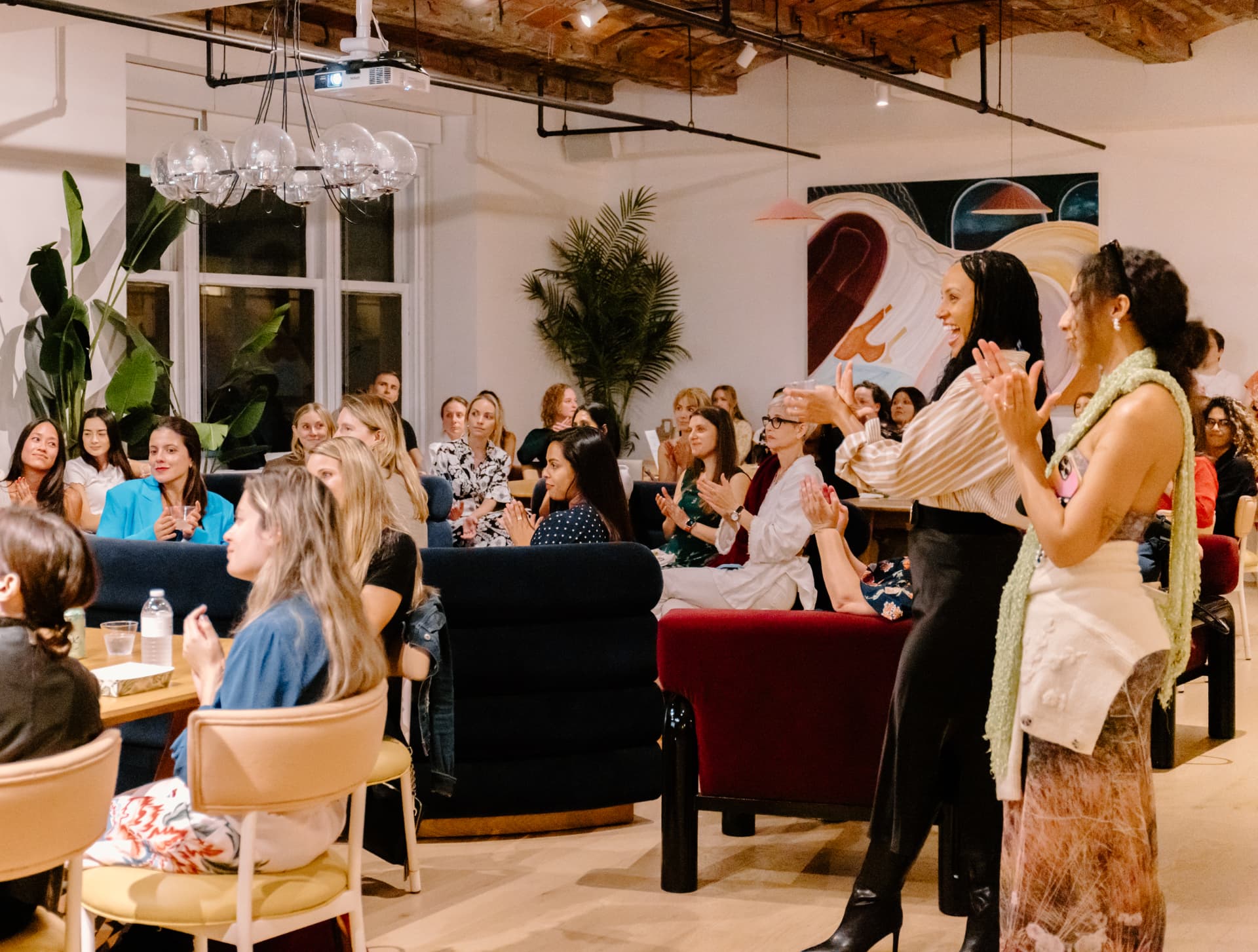 Members gathered and clapping at a Her Workplace event